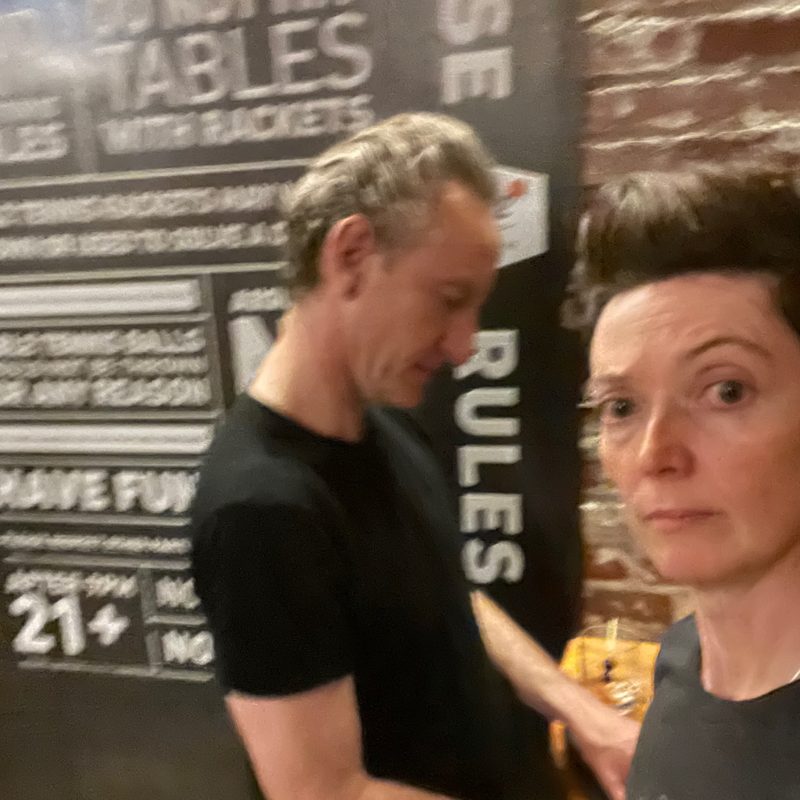 Gary and Amy in front of a ping-pong rules sign
